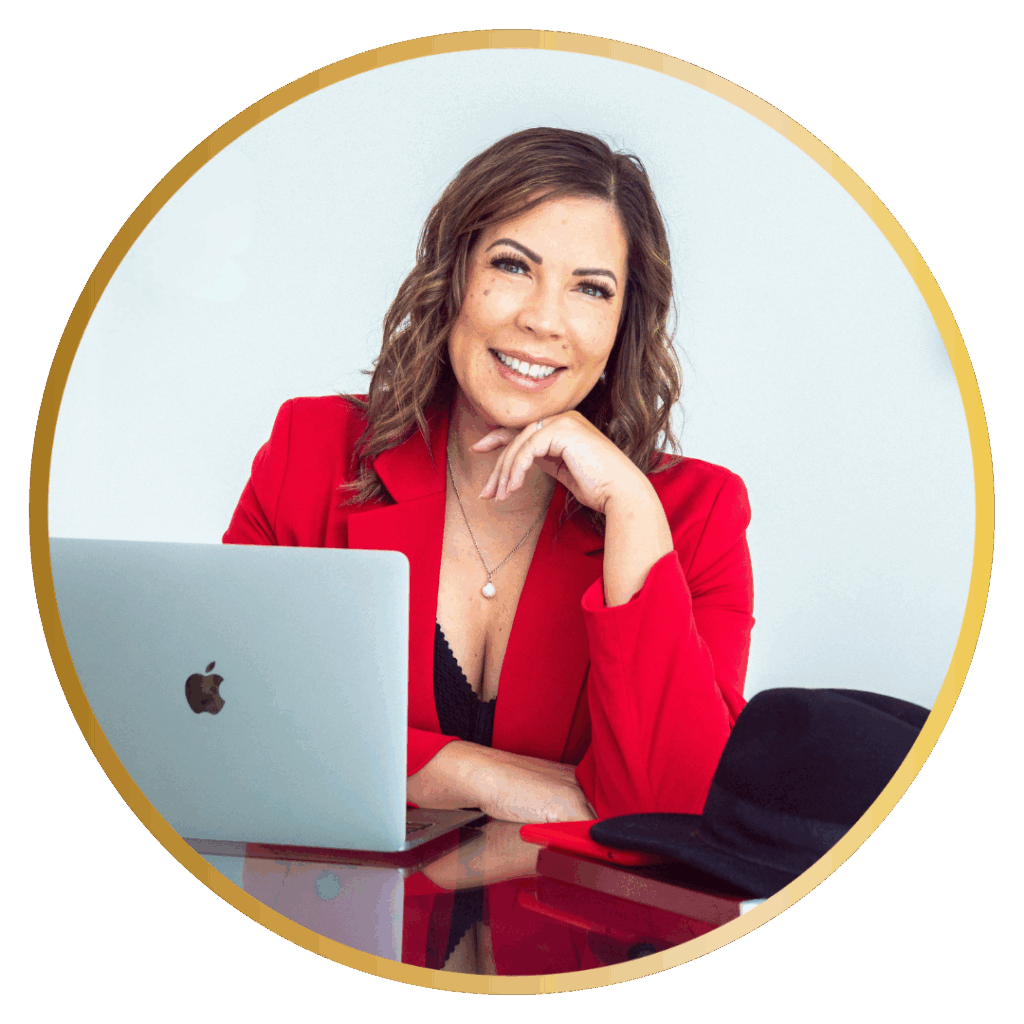 Nicole Geddes in a red jacket with her hand on her chin with her laptop in front of her